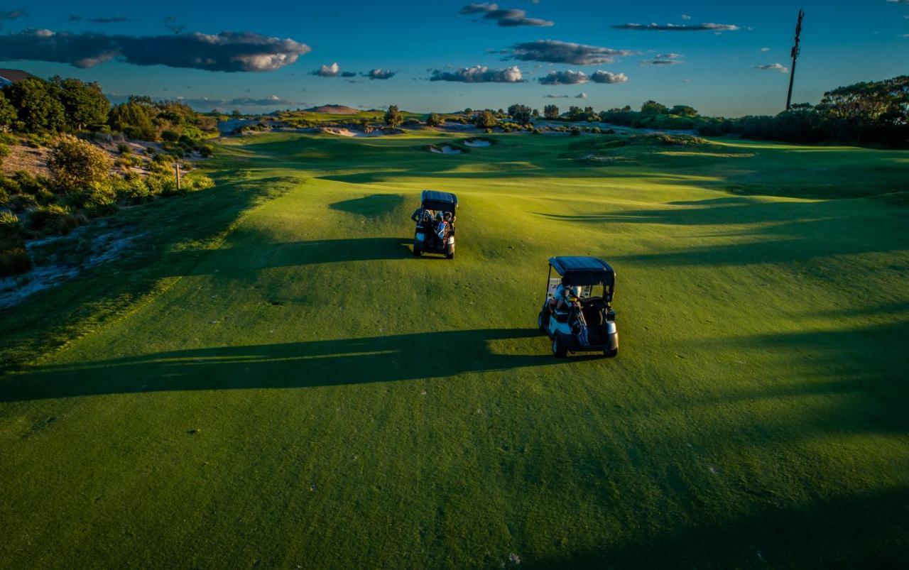 Pullman Magenta Shores Resort Entrance Exterior photo Golf carts on the green